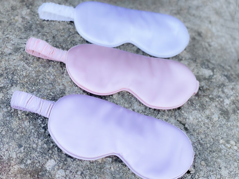 Set of 3 mulberry silk eye masks in white, pink and lilac on a rock backdrop