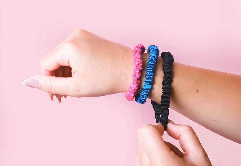 Set of hair ties on model's wrist with pink background