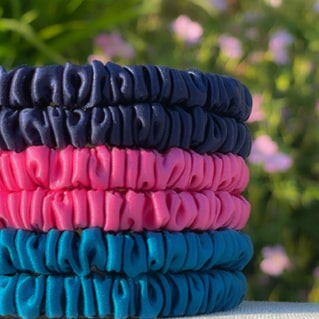 Stack of vibrant silk thin silk scrunchies in Azure Blue, Flamingo Pink and Navy Blue