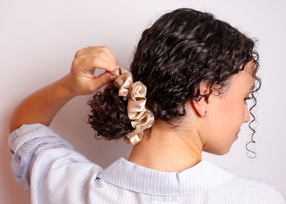 Model wearing champagne silk scrunchie with hair tied in a bun