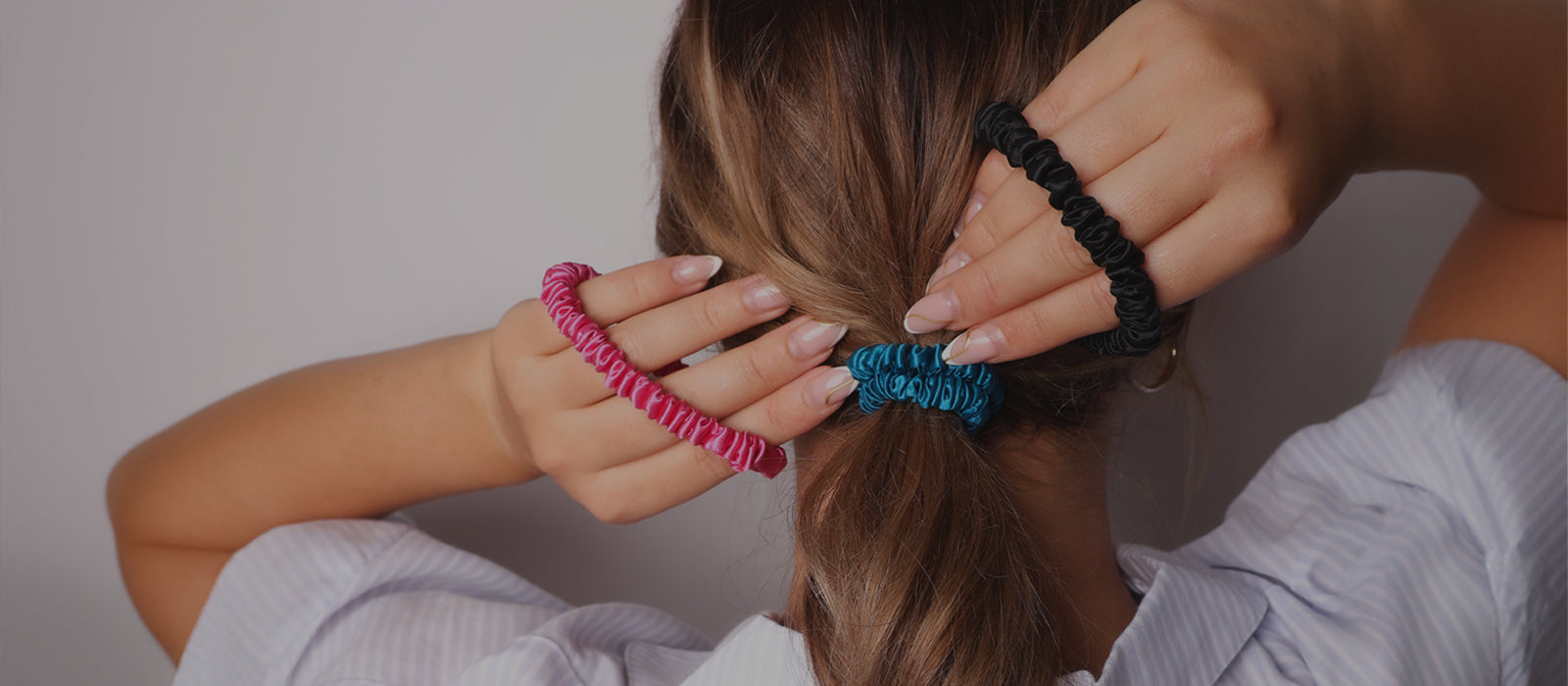 Model tying her hair up with silk hair ties - benefits of silk hair ties vs cotton