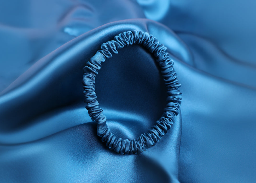 Blue silk hair bobble against matching blue silk pillowcase