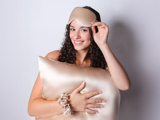 Model holding Champagne Silk Pillowcase and wearing Champagne Silk Eye Mask