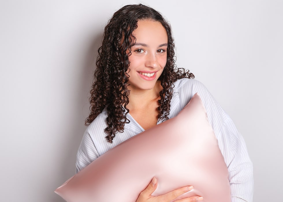 Model holding pink silk pillowcase