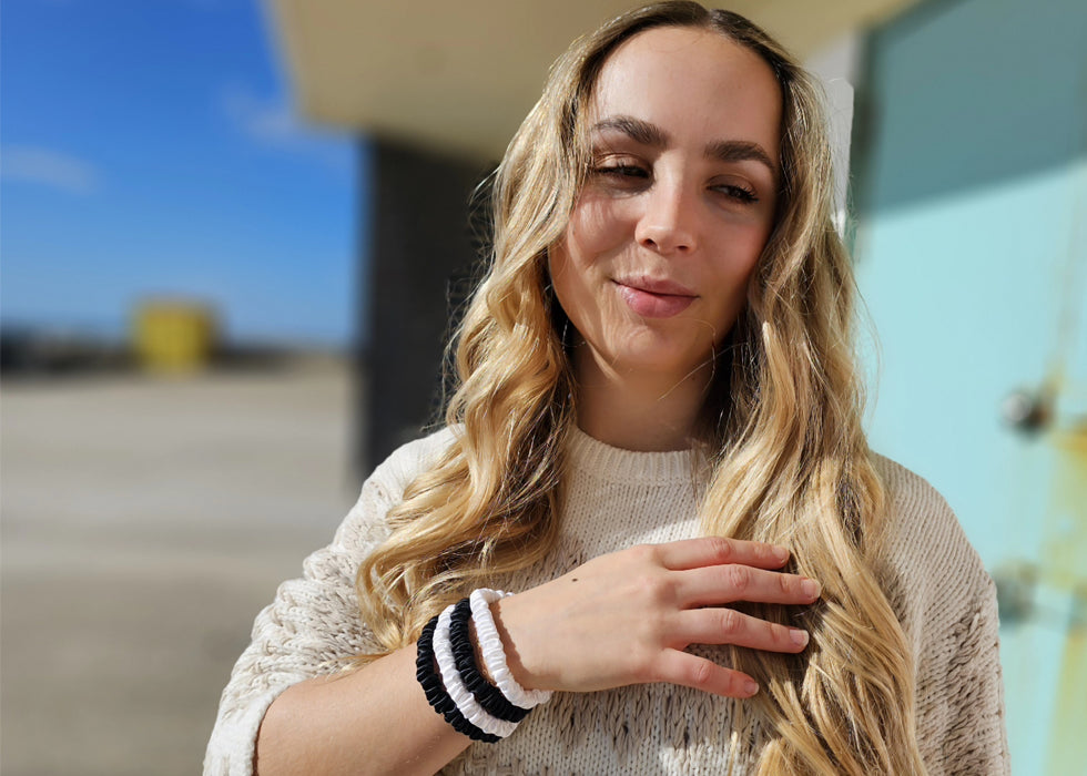 Model with long blonfe hair wearing black and white silk hair ties on her wrist