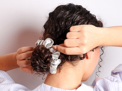 Model Wearing Hair In A Bun With A Silver Silk Scrunchie