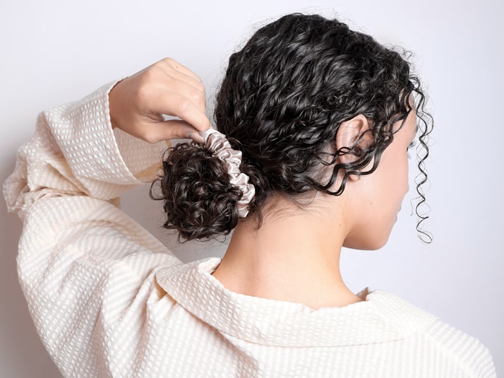 Model Wearing Hair Tied In A Bun With Small Silver Silk Scrunchie