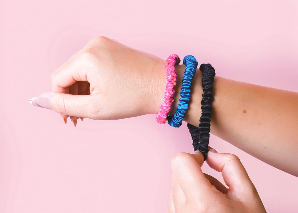 Model's wrist wearing a silk hair ties set in vibrant colours