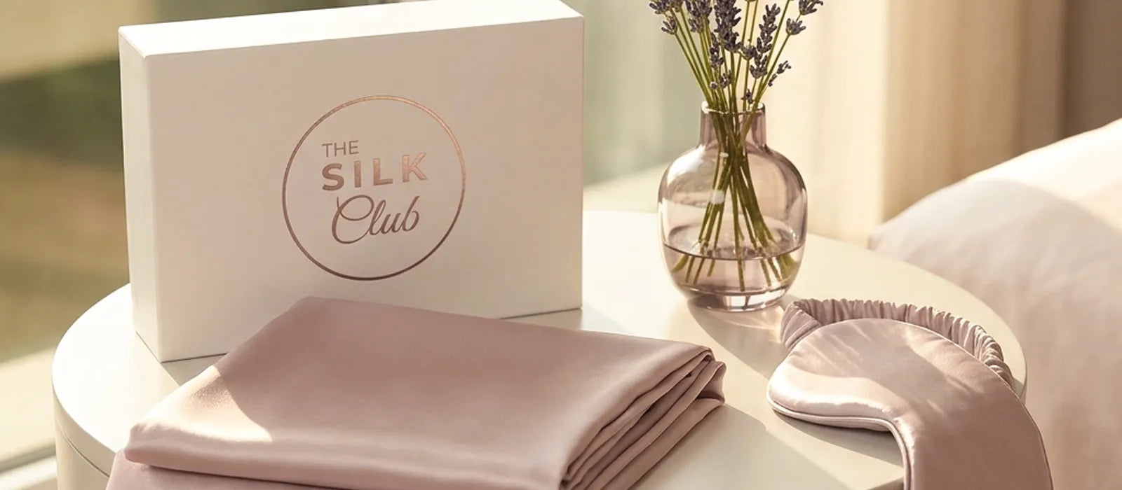Silk pillowcase and eye mask on bedside table - silk pillowcase benefits for skin, hair and sleep banner